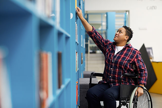 Man on a wheelchair reaching for a book